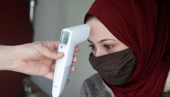 أردنية تخضع لقياس درجة الحرارة للتأكد من سلامتها من فيروس كورونا