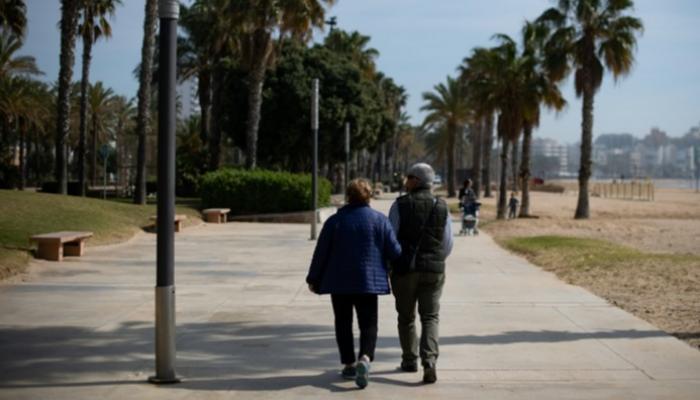 زوجان متقاعدان يتنزهان على شاطئ البحر في مدينة سالو