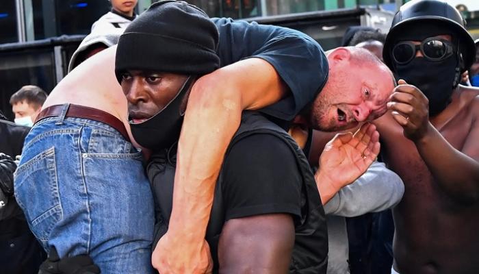 صورة الرجل صاحب البشرة السمراء وهو يحمل آخر أبيض على كتفه - الجارديان