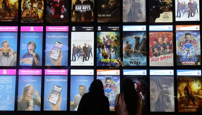 أناس يشاهدون إعلانات عروض سينمائية في مركز تجاري بدبي