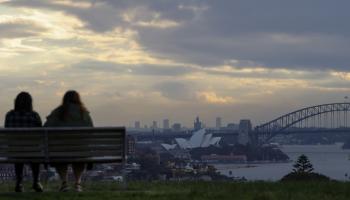 فتاتان تجلسان على مقعد يطل على دار أوبرا سيدني