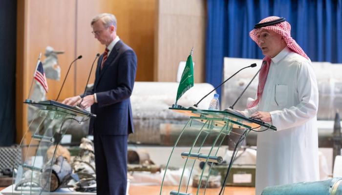 الجبير وبراين هوك في المؤتمر وخلفهما بقايا الأسلحة الحوثية