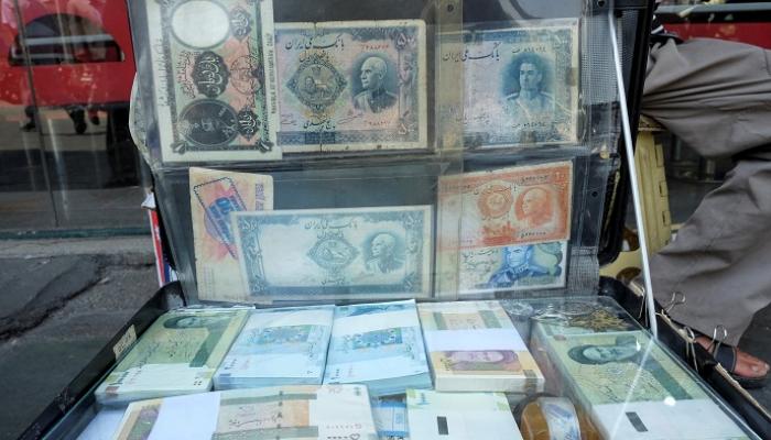 رجل يعرض العملة الإيرانية في ساحة الفردوسي في طهران- رويترز