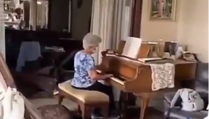 une femme joue du piano dans sa maison dévastée