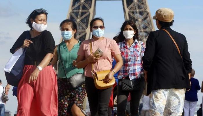 Des personnes portent un masque devant la tour Eiffel,-AFP