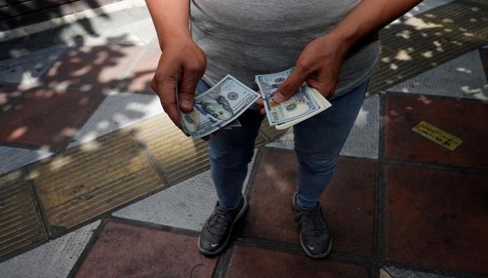 شخص يحمل عملات الدولار الأمريكي - رويترز