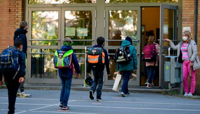طلاب يراعون التباعد الاجتماعي أثناء دخول المدرسة