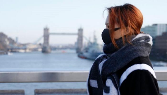  امرأة ترتدي قناعًا أثناء عبور جسر لندن