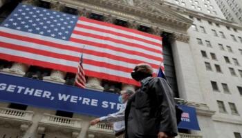  متعاملان يسيران بالقرب من بورصة نيويورك - رويترز 