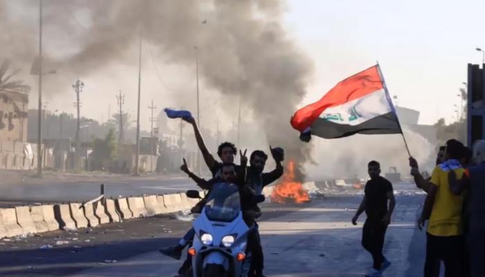 عراقي يرفع علم بلاده في مظاهرات سابقة