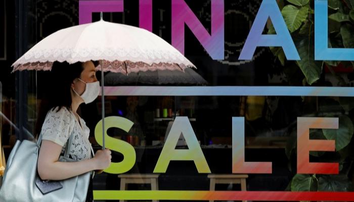 يابانية تمر أمام واجهة أحد المحلات التجارية