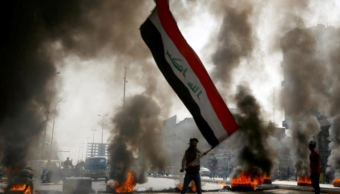متظاهر عراقي يحمل علم بلاده خلال مواجهات سابقة