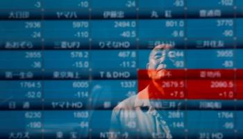 شخص يقف أمام شاشة للتداول في بورصة طوكيو