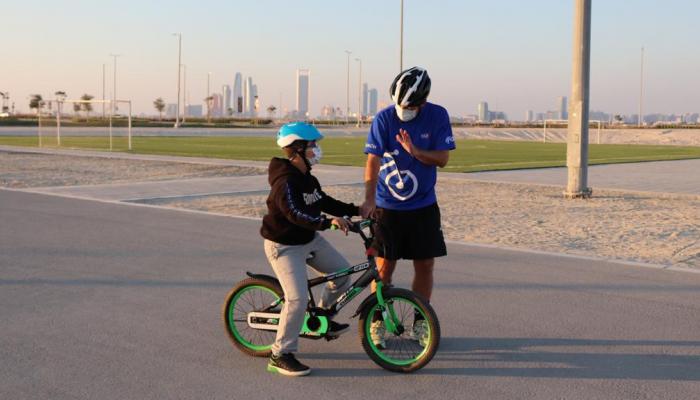 مدرب يعلم طفلا من أصحاب الهمم ركوب الدراجة
