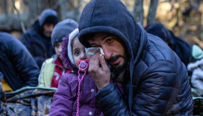 مهاجر وأسرته على الحدود بين بيلاروسيا وبولندا