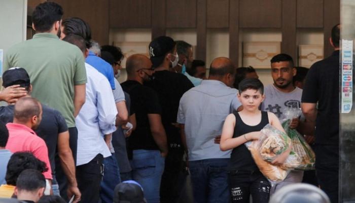 طفل لبناني يحمل ربطة خبز وسط زحام أمام منفذ البيع