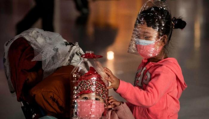 طفلتان تحميان وجهيهما بقارورتي مياه للوقاية من فيروس كورونا في الصين
