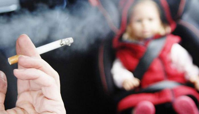 طفل وبجواره شخص يدخن سيجارة - تعبيرية