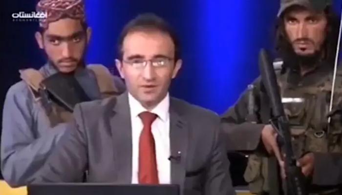 مشهد من الفيديو المتداول لمسلحين من طالبان يقفون خلف مذيع تلفزيوني