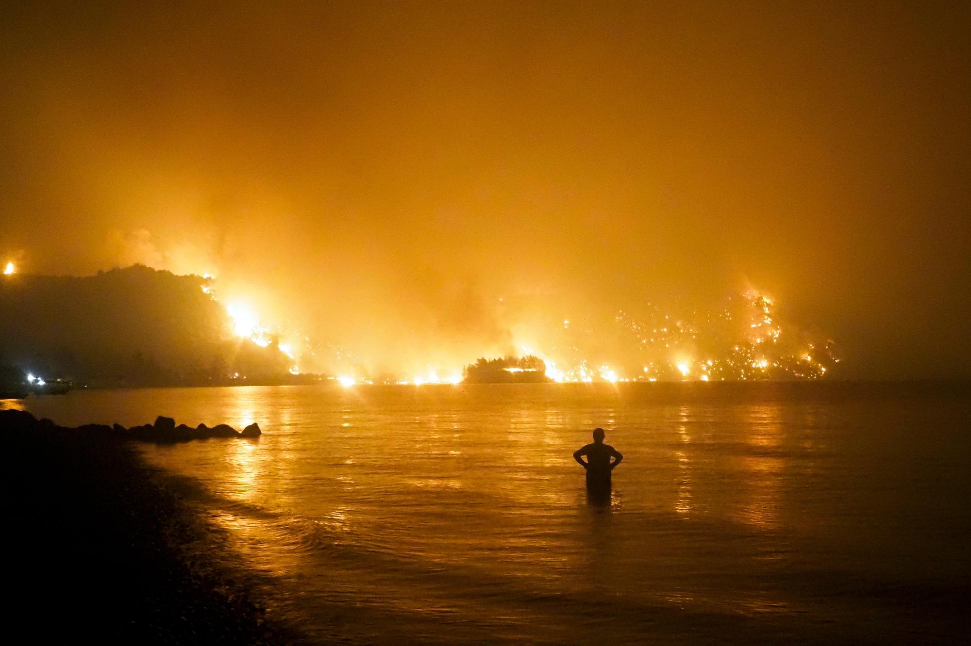 مردی آتش سوزی در ساحل کوچیلی در نزدیکی روستای لیمنی یونان تماشا می‌کند