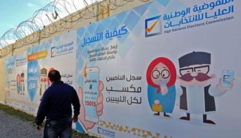 مواطن ليبي بجوار لافتة تدعو للانتخابات التي تم إلغاؤها