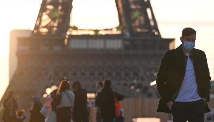 شاب يرتدي كمامة للوقاية من فيروس كورونا أمام برجل إيفل في باريس