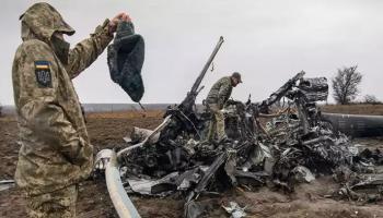 جندي أوكراني يتفحص بقايا مروحية مي8 الروسية