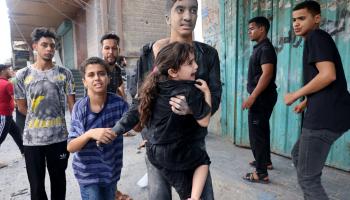 فتى يحمل طفلة صغيرة إثر غارة إسرائيلية على غزة
