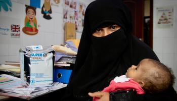 سيدة يمنية مع طفلها الذي يعاني سوء التغذية في أحد المراكز الصحية. - أرشيفية
