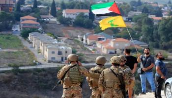 أنصار حزب الله يرفعون راية الحزب وعلم فلسطين أمام جنود لبنانيين