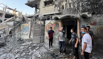 فلسطينيون يقفون وسط حطام منازل دمرها قصف إسرائيلي بغزة - رويترز