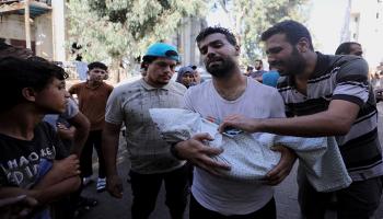 فلسطيني يحمل جثمان طفله الذي توفي جراء القصف الإسرائيلي على غزة