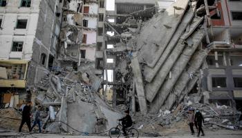 فلسطينيون يسيرون وسط الأنقاض بمدينة غزة