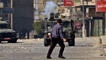 شاب فلسطيني يمسك بحجر وهو يواجه مركبة عسكرية إسرائيلية خلال عملية نابلس