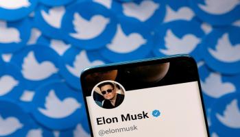 حساب إيلون ماسك على Twitter على هاتف ذكي موضوع على شعارات تويتر - رويترز