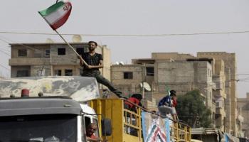 شخص يلوح بالعلم الإيراني في سوريا - المرصد السوري