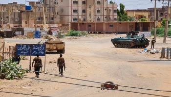 جنود الجيش السوداني يسيرون قرب عربات مدرعة متمركزة في أحد شوارع جنوب الخرطوم