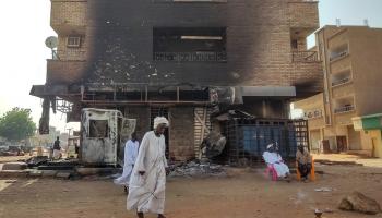 سودانيون قرب مبنى دمرته الاشتباكات بالخرطوم - الفرنسية