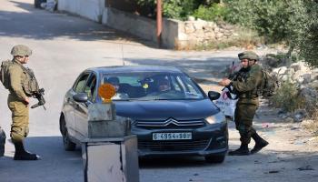 جنود إسرائيليون يقفون على حاجز على مدخل قرية عوريف الفلسطينية، جنوب مدينة نابلس