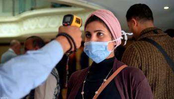 فتاة ترتدي كمامة تخضع لقياس حرارة في مصر