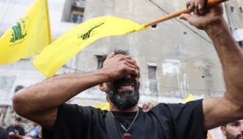 رجل يبكي وهو يحمل علم حزب الله خلال جنازة الأشخاص الذين قتلوا بعد تفجيرات بيجر