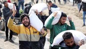 فلسطينيون يحملون أجولة الطحين في غزة - رويترز