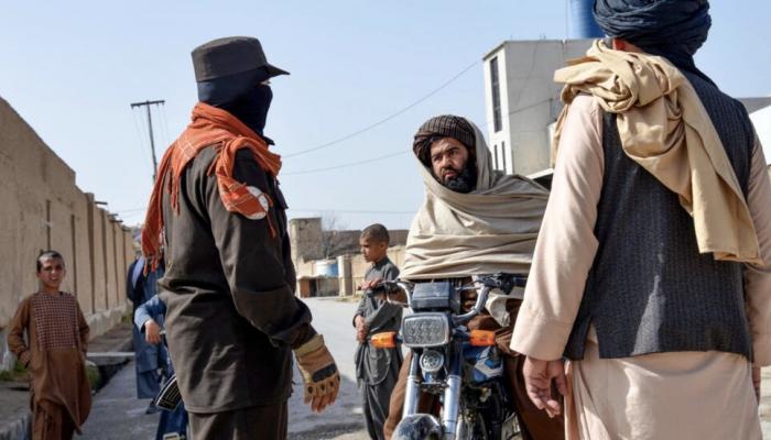 عنصر أمن أفغاني يفتش شخصا بموقع التفجير