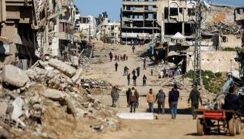 فلسطينيون يسيرون وسط دمار خلفه القصف الإسرائيلي على غزة - أرشيفية