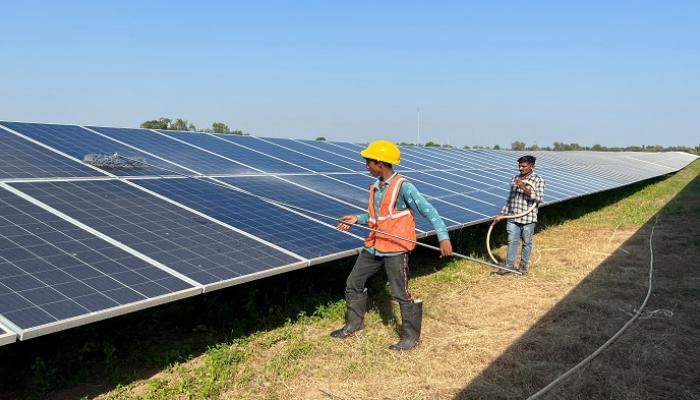 عمال يقومون بتنظيف الألواح في حديقة للطاقة الشمسية في مودهيرا - رويترز