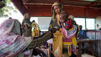 لاجئة سودانية تحمل طفلها في معسكر لجوء شمال دارفور