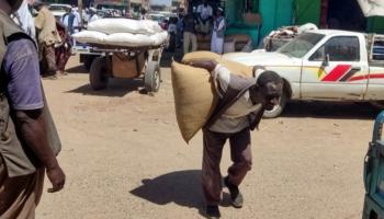 سوداني ينقل شوالا من محصول على ظهره - AFP