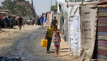 طفلان فلسطينيان ينقلان المياه بمخيم في دير البلح