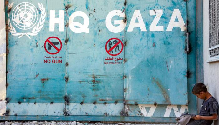 طفل يجلس أمام مدخل مبنى الأونروا في غزة