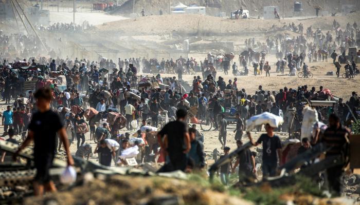 فلسطينيون يحملون أكياسًا من المساعدات الإنسانية قرب ممر نتساريم